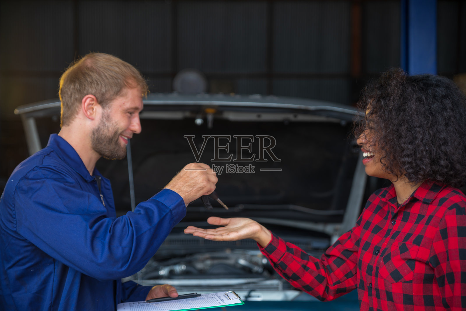 一位女顾客从机械工程师那里拿到了车钥匙。照片摄影图片