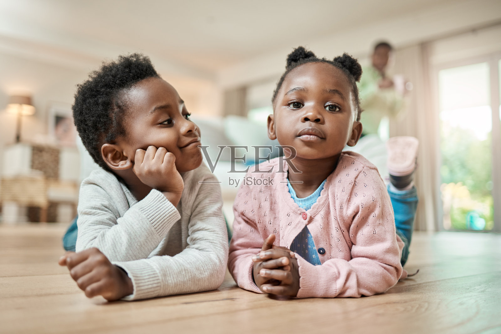 一个可爱的小女孩和她的弟弟躺在家里客厅的地板上照片摄影图片