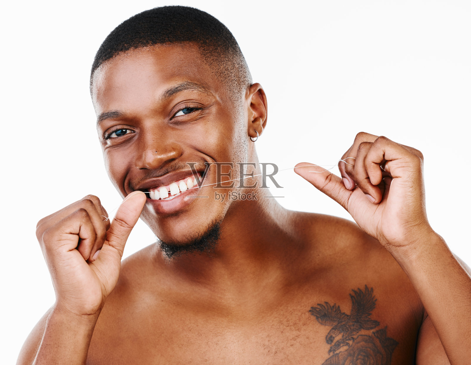 一个英俊的年轻人在白色背景下用牙线清洁牙齿的画室肖像照片摄影图片