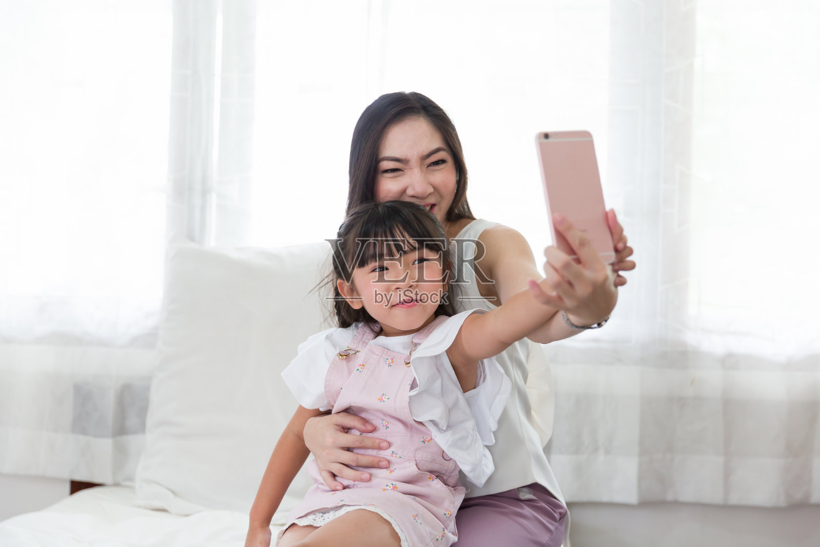 母女在家用智能手机自拍，家人在家用手机玩得开心。照片摄影图片