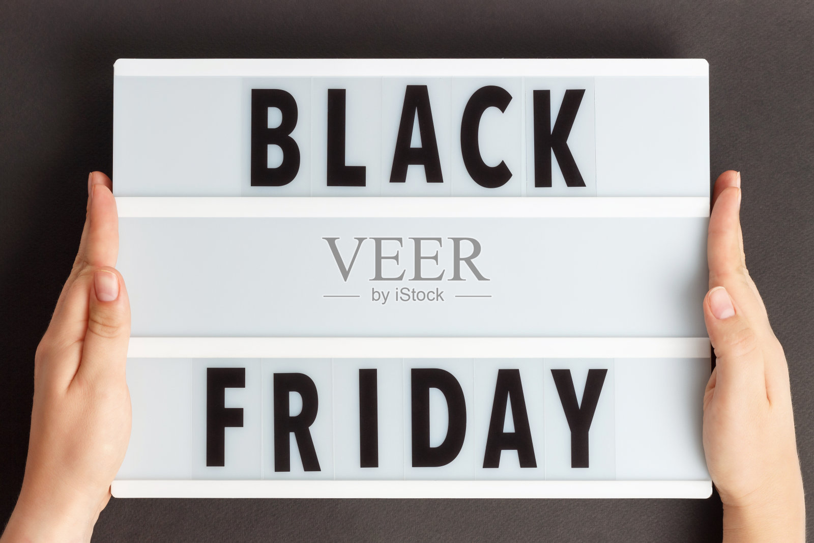 女性手持灯箱，背景上有黑色星期五的字样。照片摄影图片