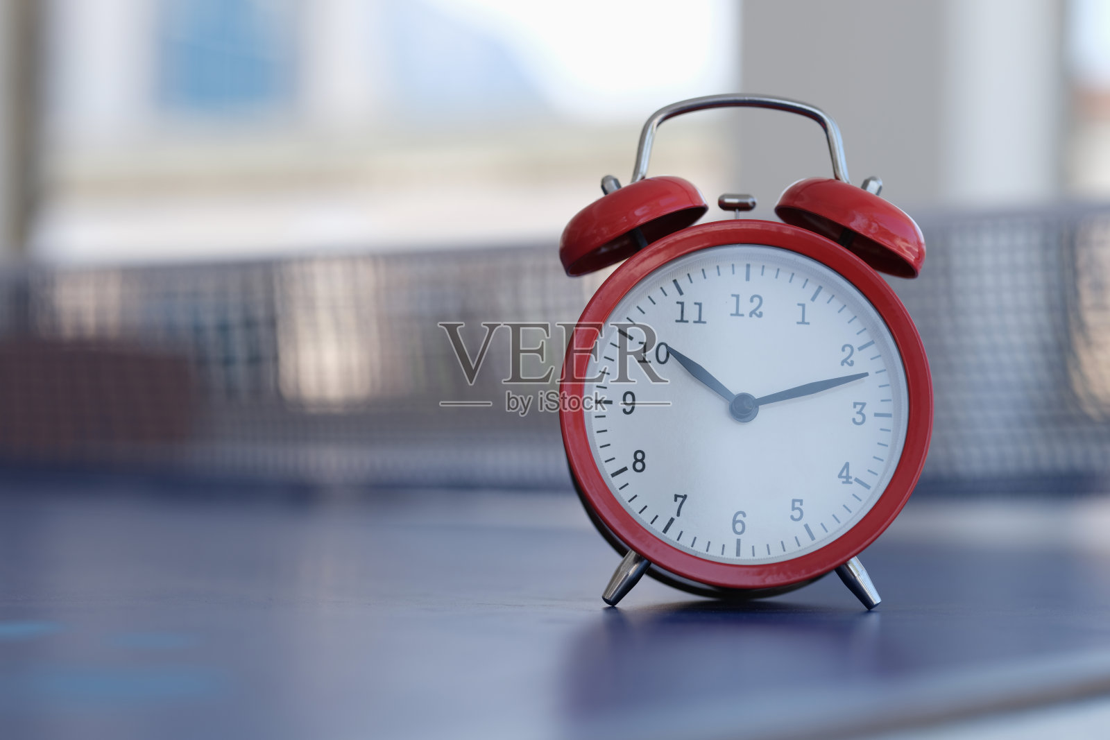 红色闹钟站在网球桌上特写照片摄影图片