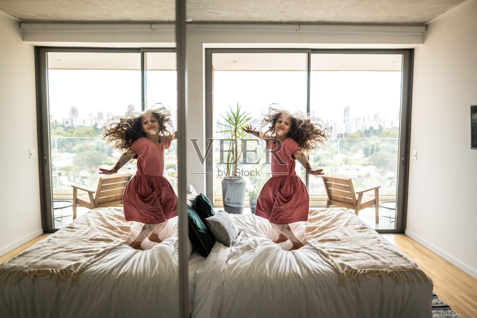 花斑症的女孩在家里的床上蹦蹦跳跳照片摄影图片