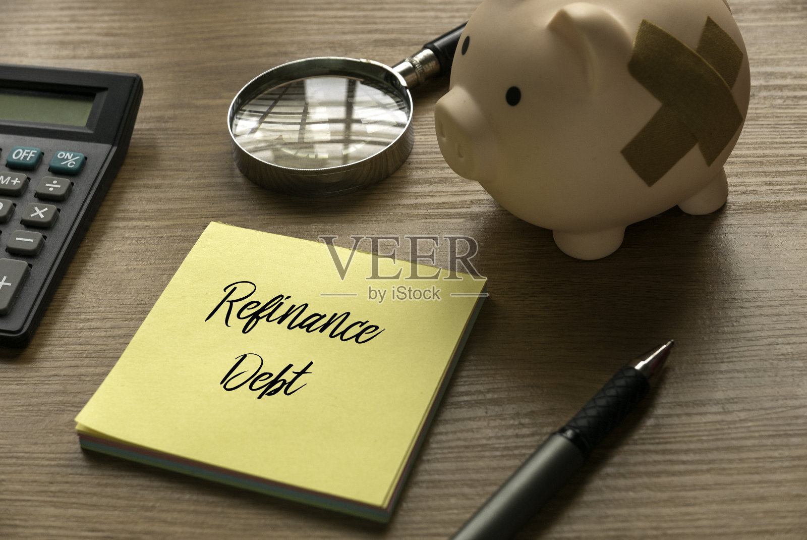 选择焦点的计算器，放大镜，存钱罐，钢笔和备忘录写的再融资债务木制背景。照片摄影图片