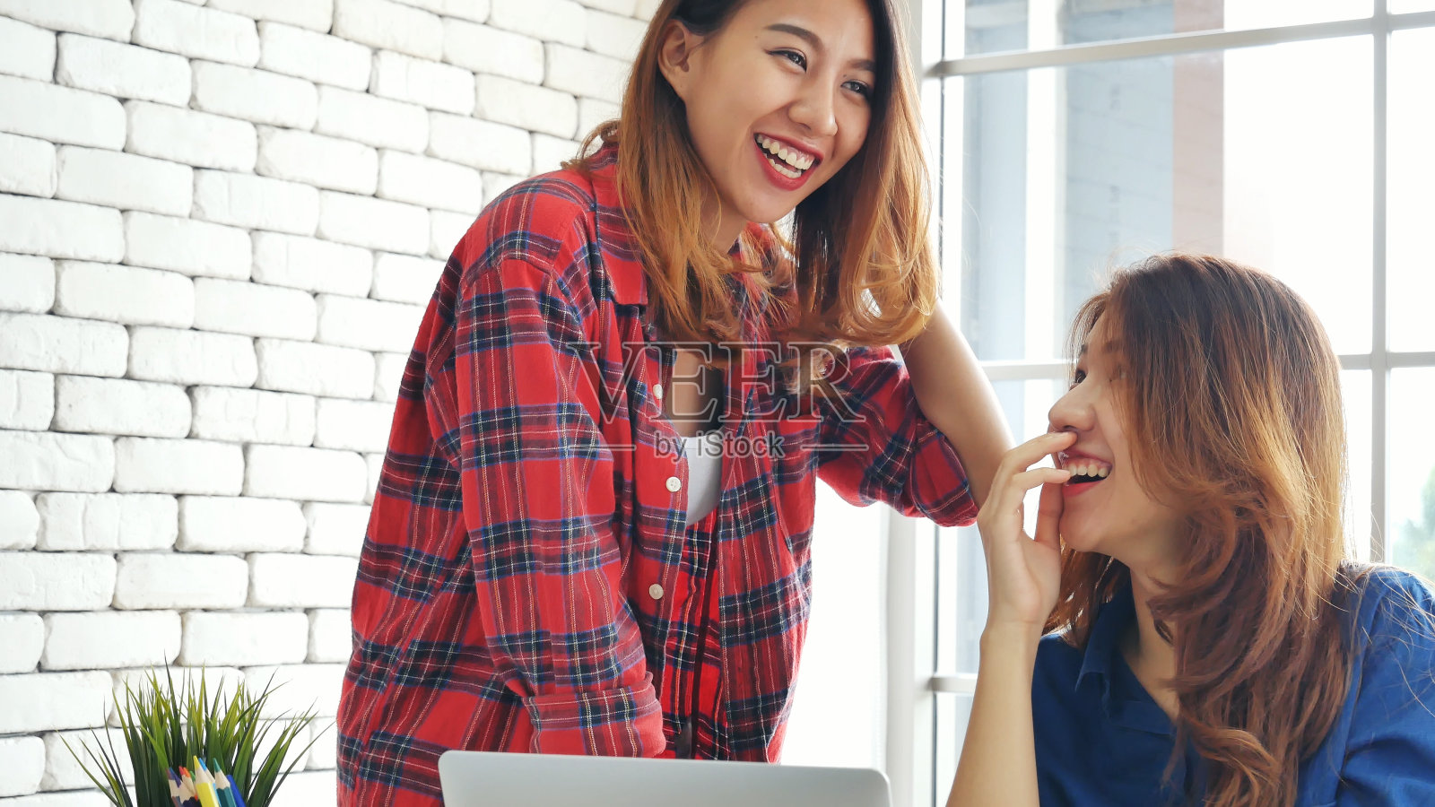 亚洲同事友谊在工作中笑脸相迎。幸福两个女同事一起工作，小组会议在办公桌上。团队业务伙伴与电脑笔记本电脑创业公司照片摄影图片