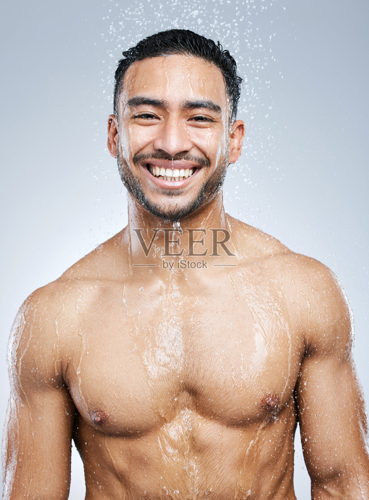 一个英俊的年轻男子在灰色背景下洗澡的画室肖像照片摄影图片