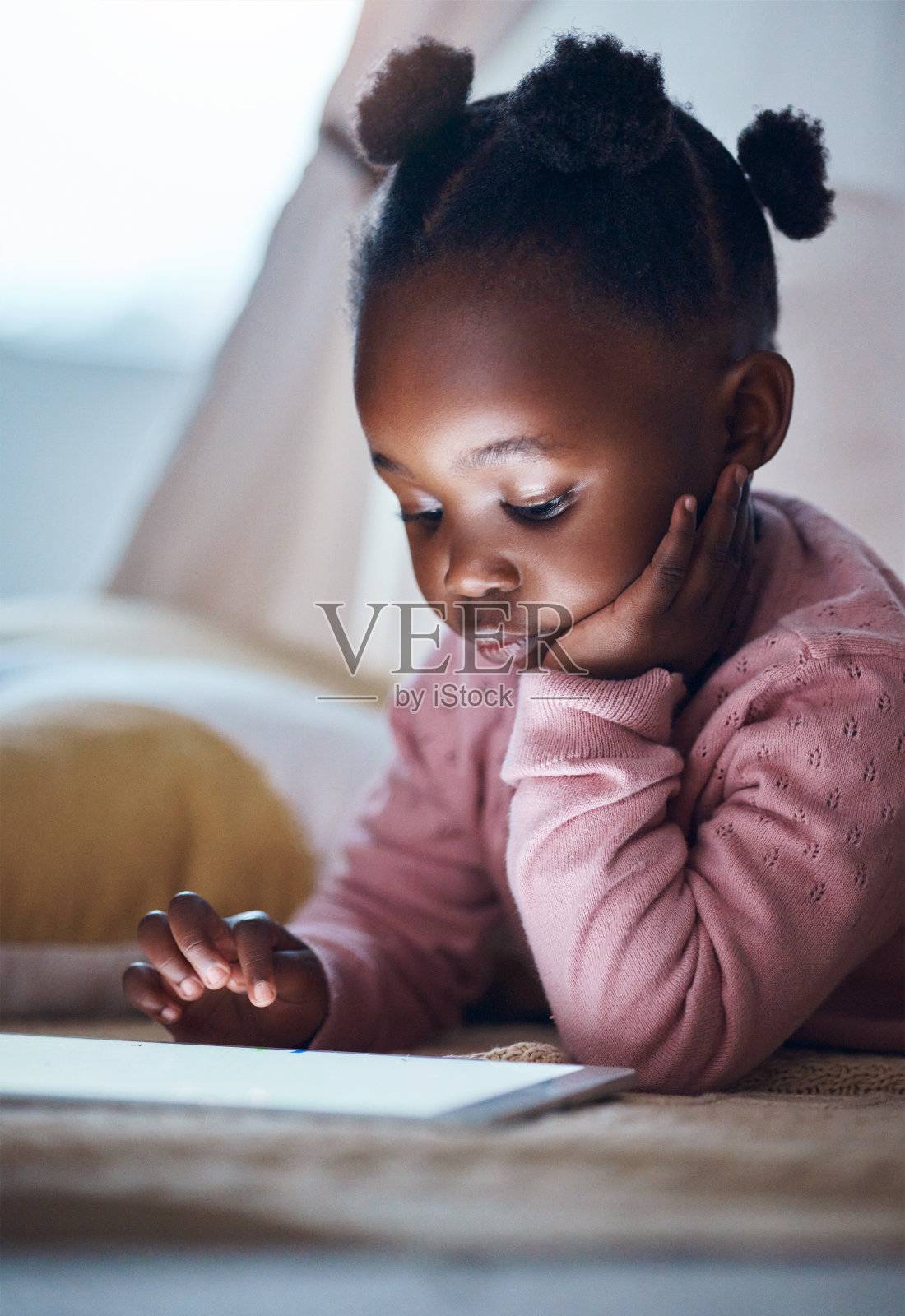 一个小女孩在她的卧室里使用平板电脑照片摄影图片