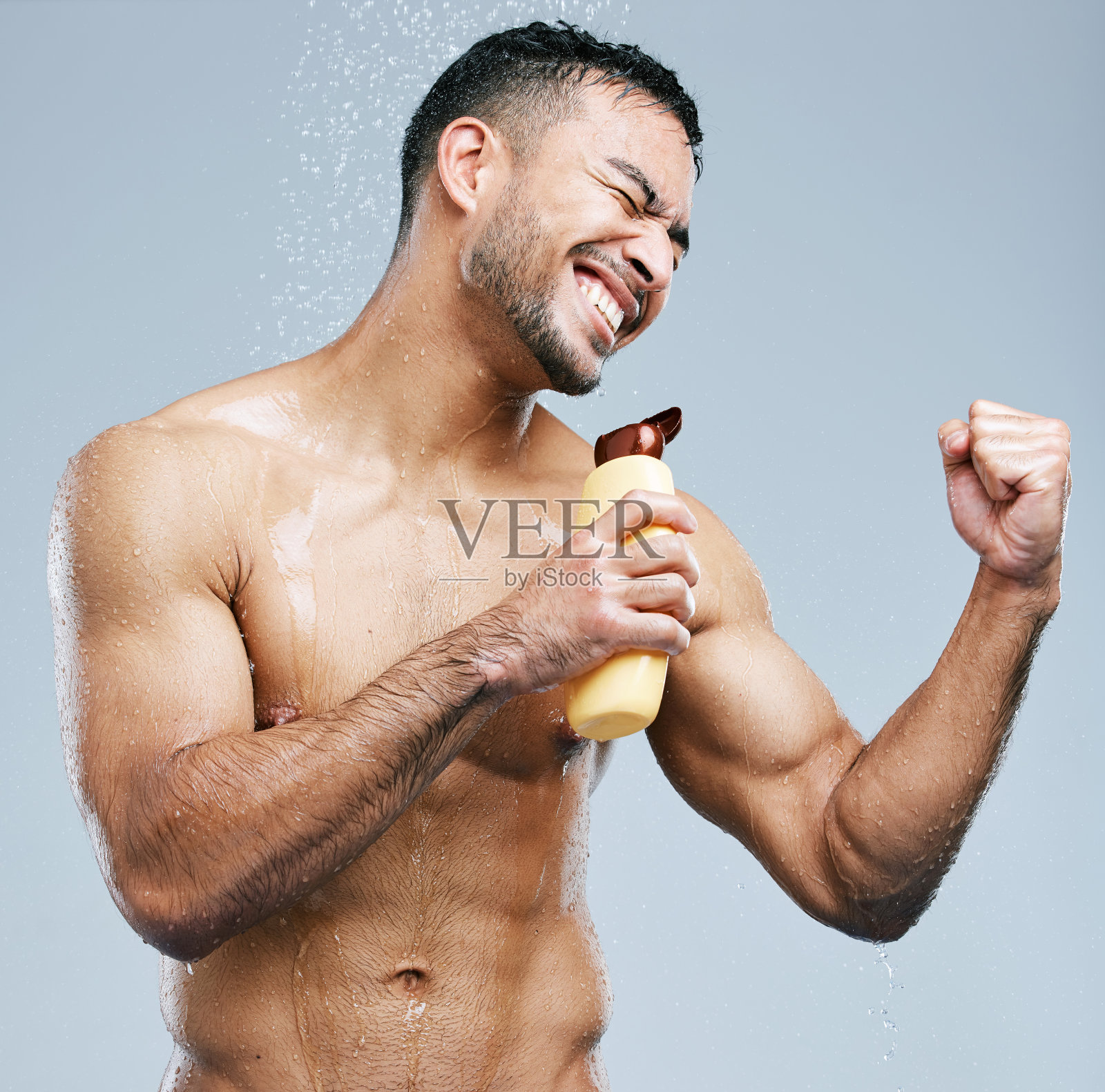 摄影棚拍摄了一个英俊的年轻人在淋浴时唱歌，背景是灰色的照片摄影图片