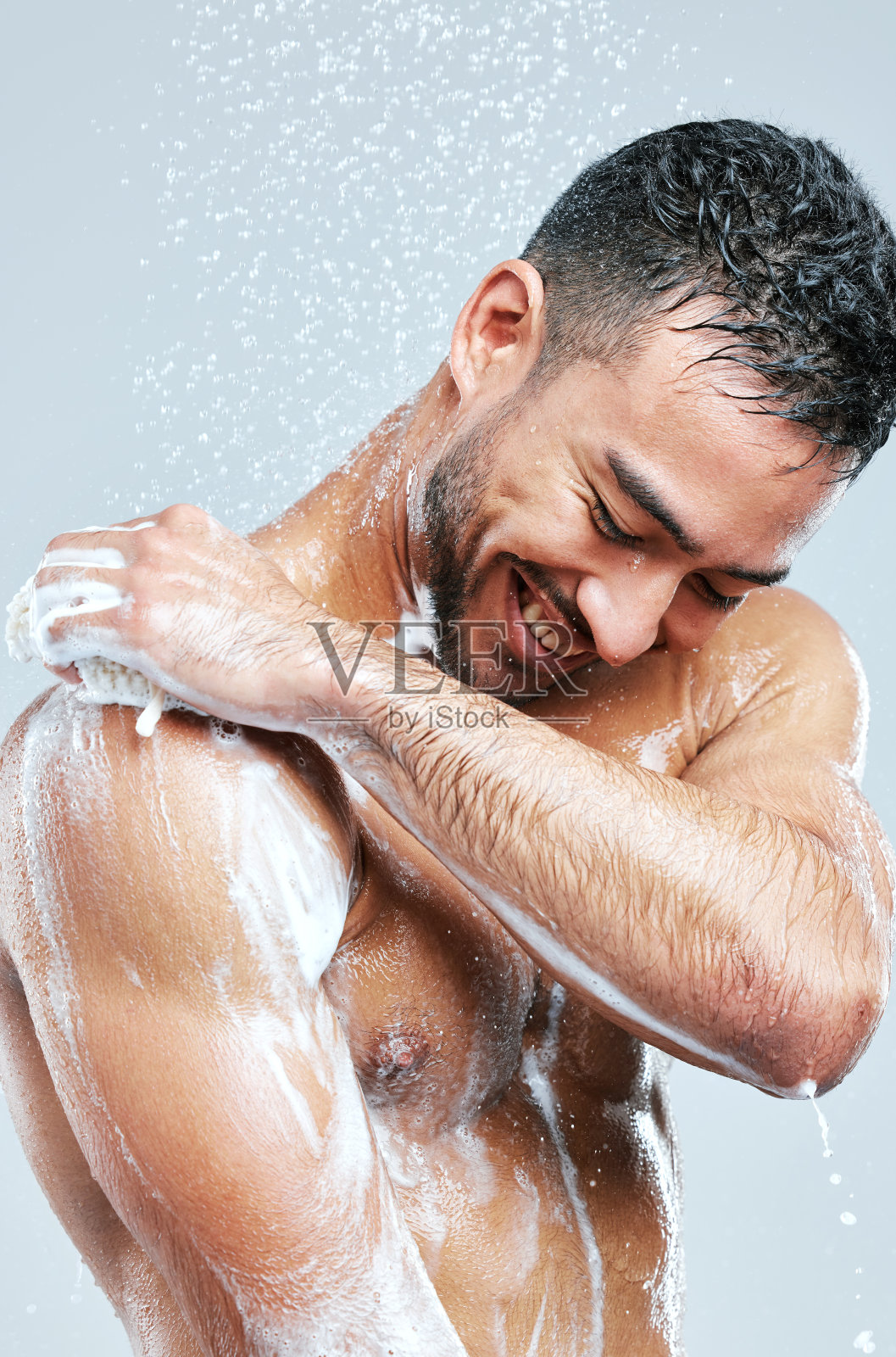 摄影室拍摄的一个英俊的年轻男子淋浴在灰色的背景照片摄影图片