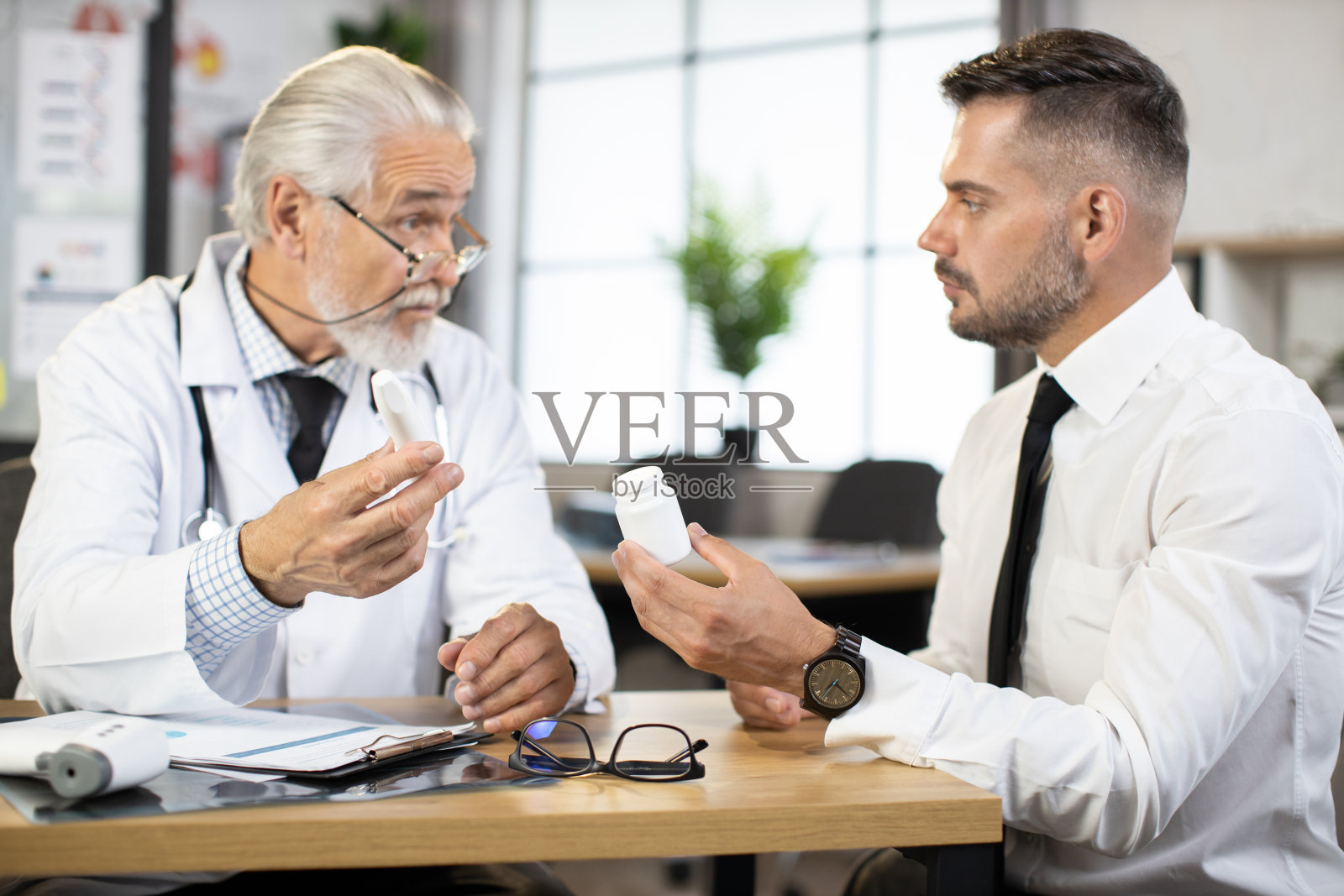 成熟的治疗师向男性病人咨询有关药片的问题照片摄影图片