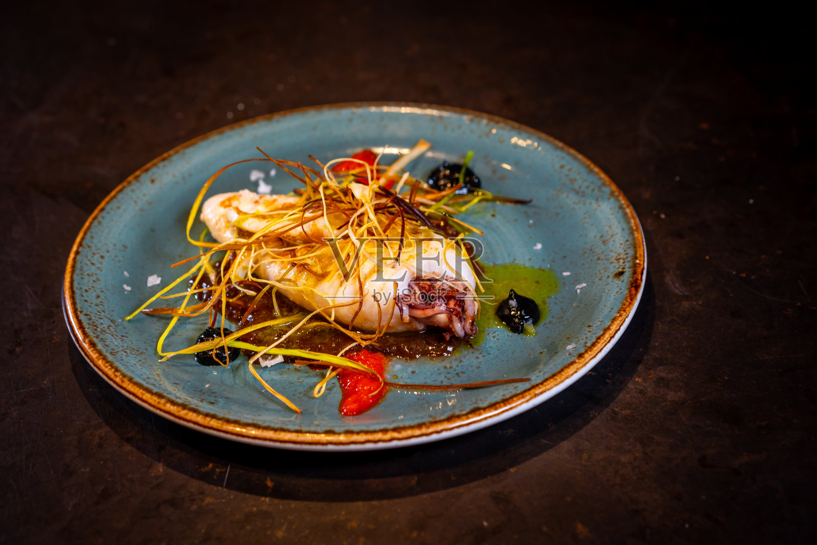 炸鱿鱼酱，黑色背景，绿色盘子照片摄影图片