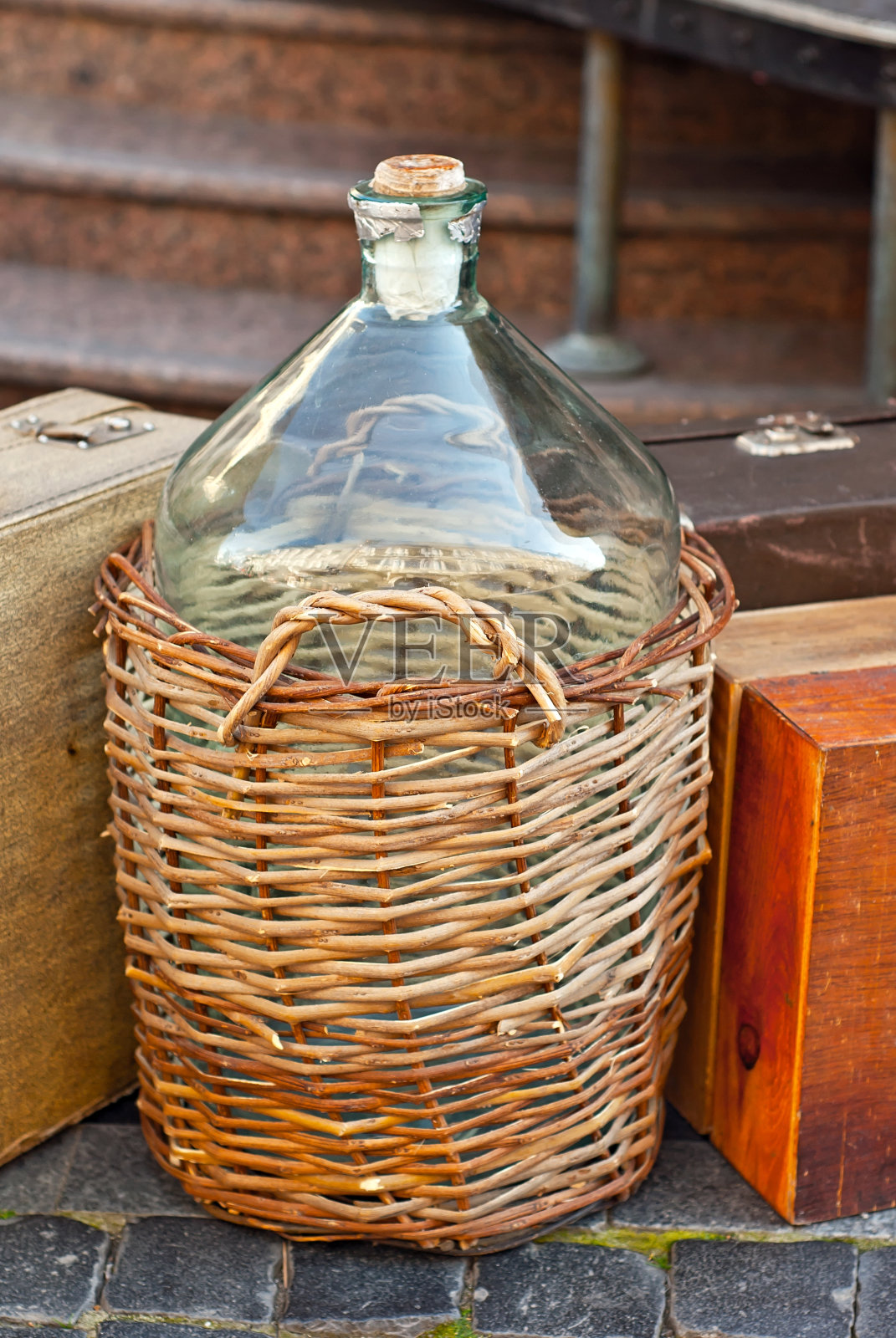 藤蔓缠绕在一个大瓶子上。葡萄酒发酵篮收起来。篮子里的玻璃瓶。照片摄影图片