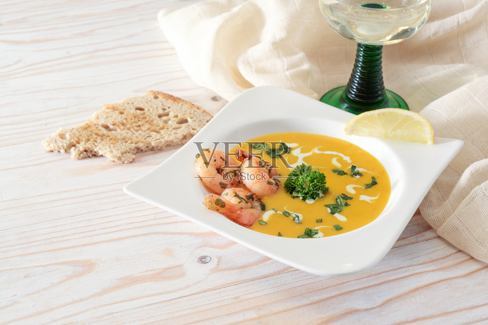 节日蔬菜奶油汤，红栗南瓜配虾和欧芹在白色盘子，面包和葡萄酒在一个轻型木桌为感恩节或万圣节，复制空间照片摄影图片