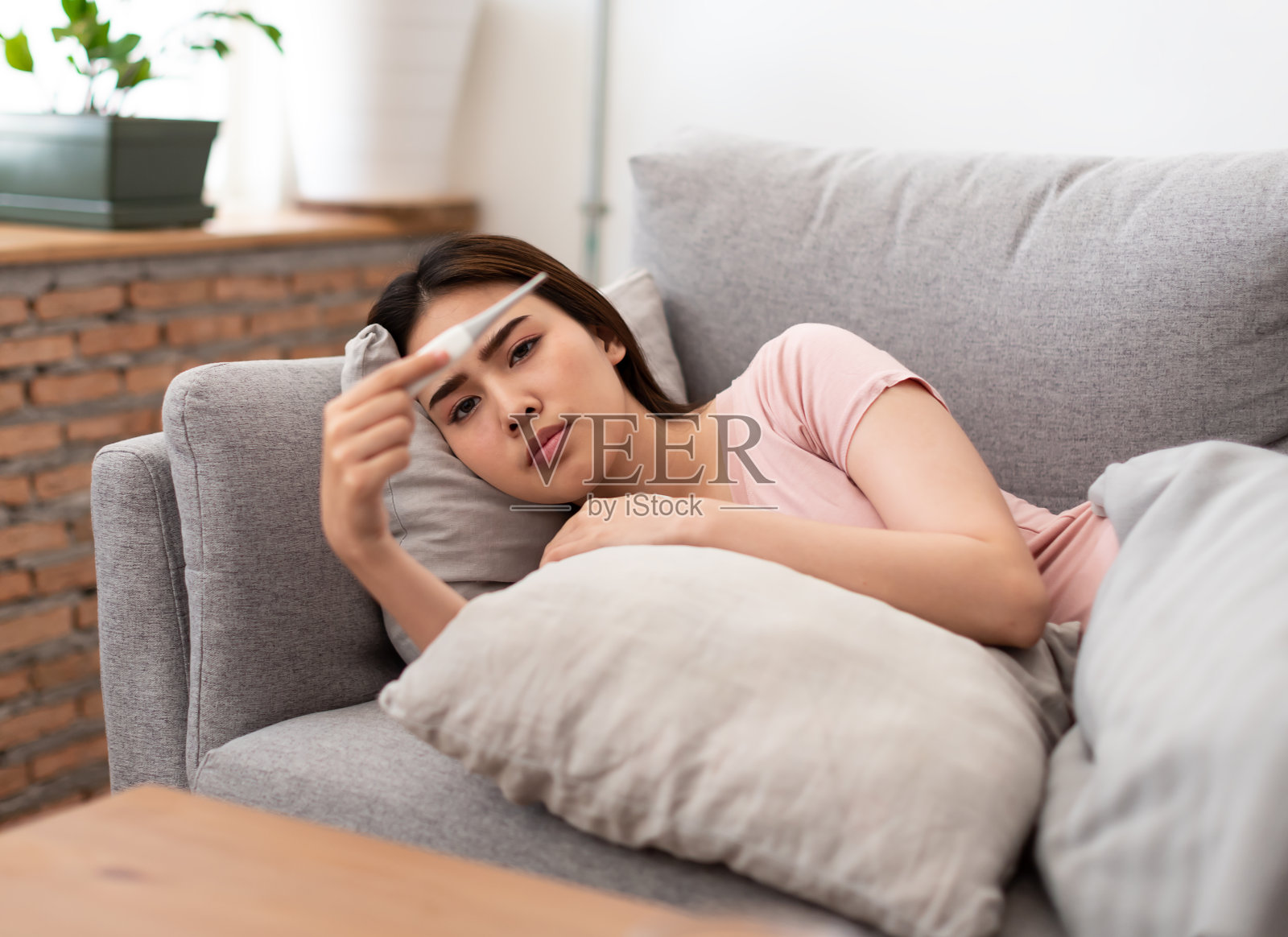 亚洲年轻女子生病，身体不适，冷，测量体温后拿着温度计。照片摄影图片