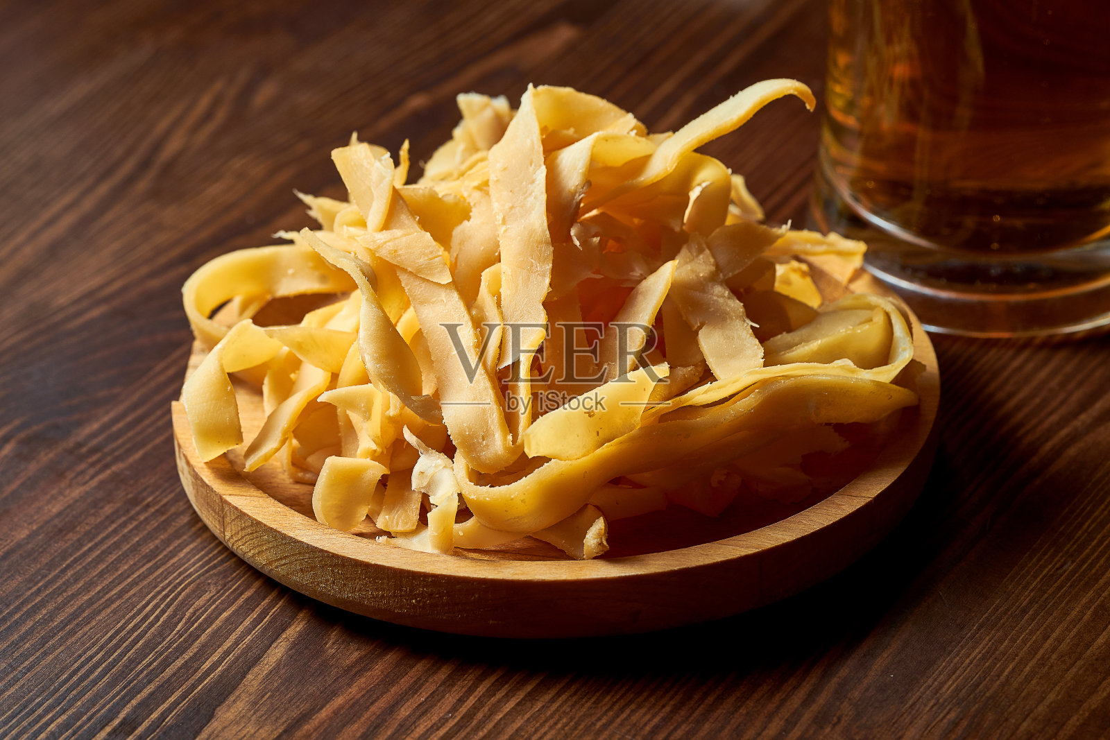 美味的啤酒小吃-干燥和咸鱿鱼圈在一个木制的盘子。照片摄影图片