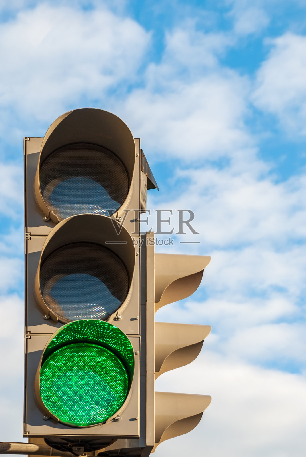 以红绿灯为背景，天空中点缀着云朵。信号的绿色。照片摄影图片