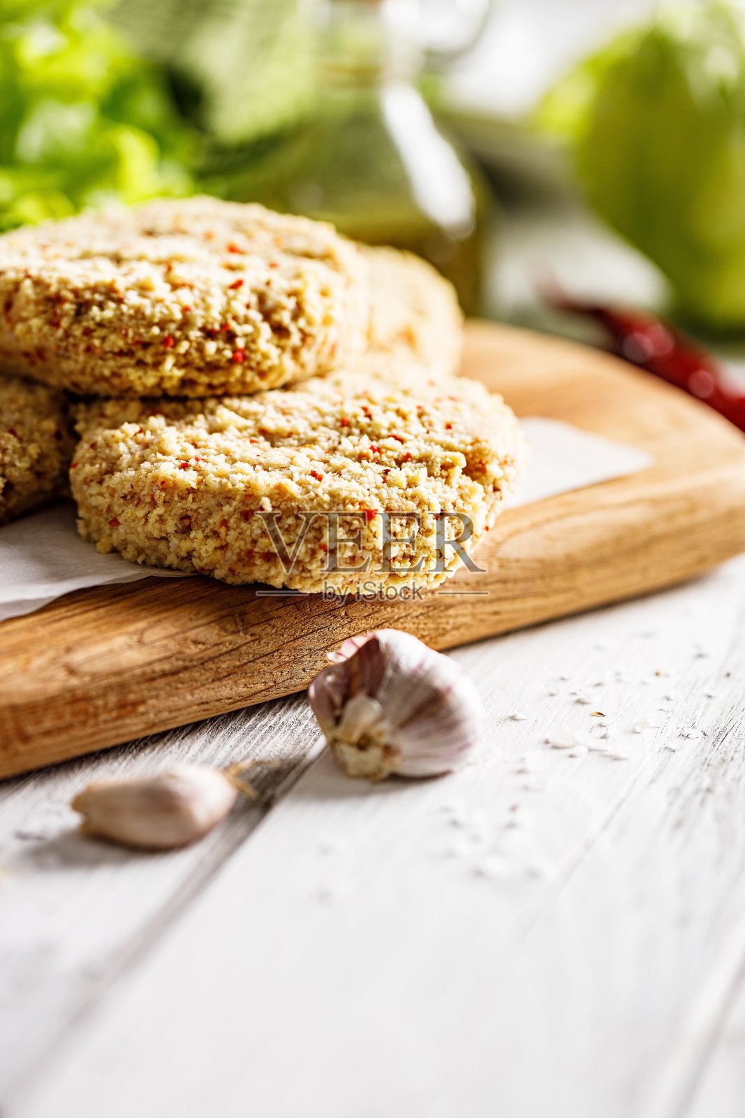 垂直切生鸡肉汉堡肉片，撒上辣椒粉和大蒜。用香料自制的家禽肉片。白色的背景。本空间照片摄影图片