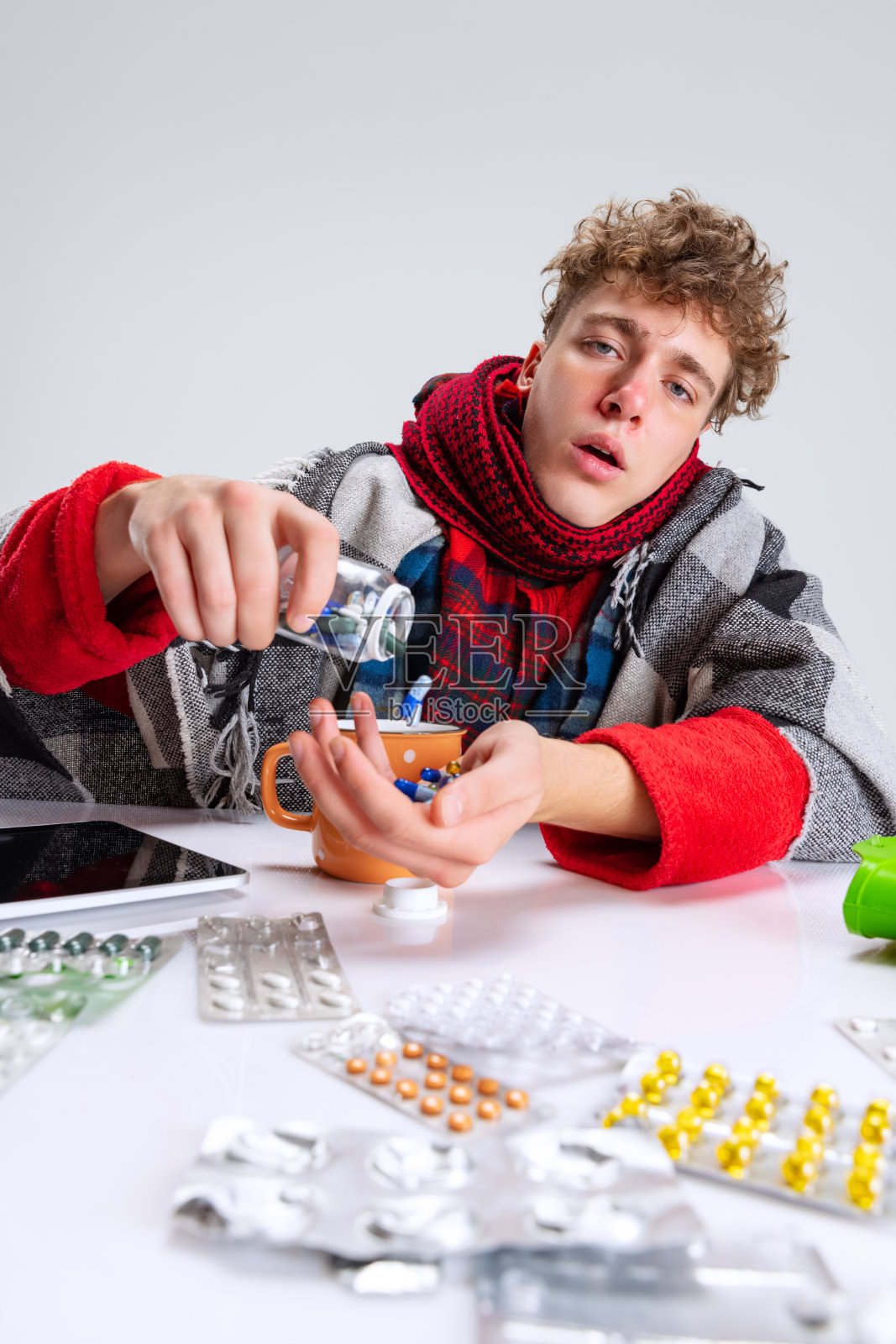 生病的男孩的肖像，患感冒和流感包围的药丸孤立的灰色背景。Self-isolation照片摄影图片