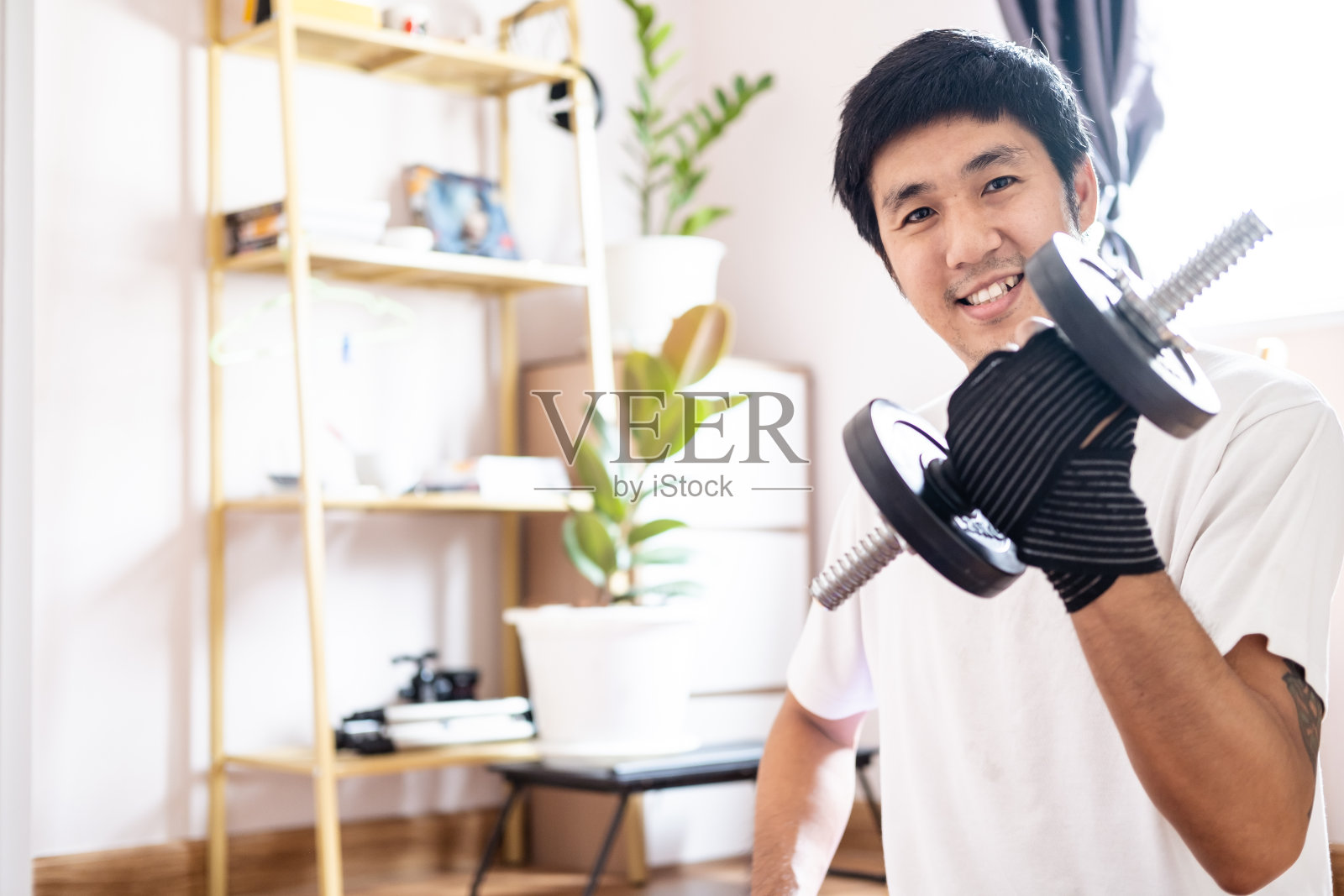 亚洲白人男子持哑铃在家训练锻炼体重教练在室内锻炼运动锻炼健康积极体重健康生活方式照片摄影图片