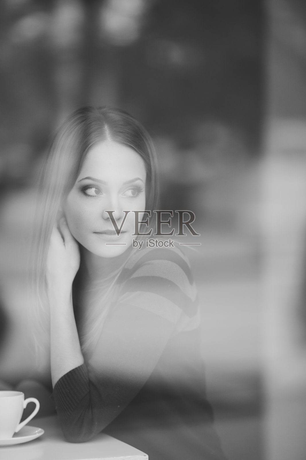 一个可爱微笑的年轻女子的肖像在咖啡馆的桌子上喝着一杯茶。照片摄影图片