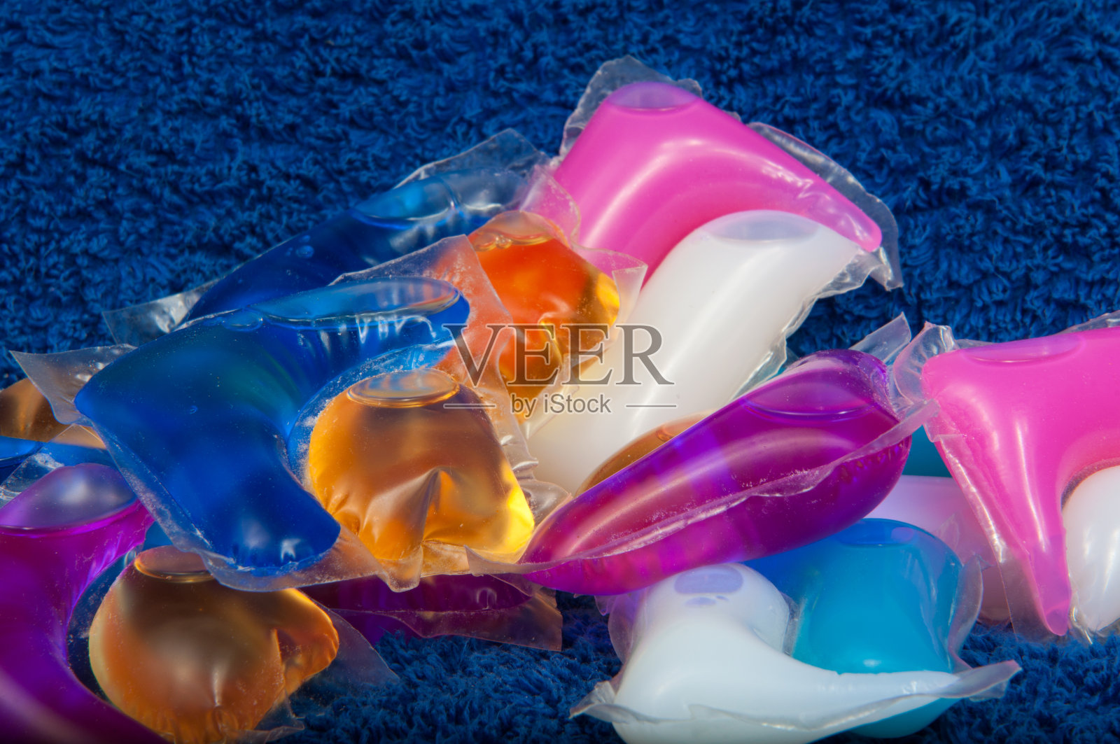 洗色凝胶胶囊在蓝色布的质地上照片摄影图片