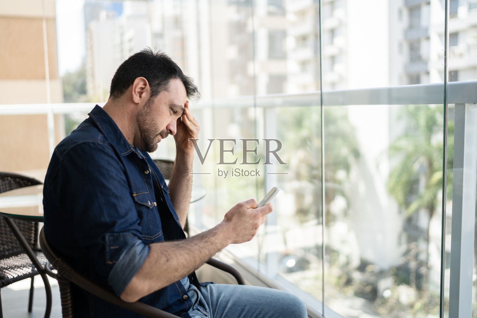 一个忧心忡忡的男人在公寓阳台上使用智能手机照片摄影图片