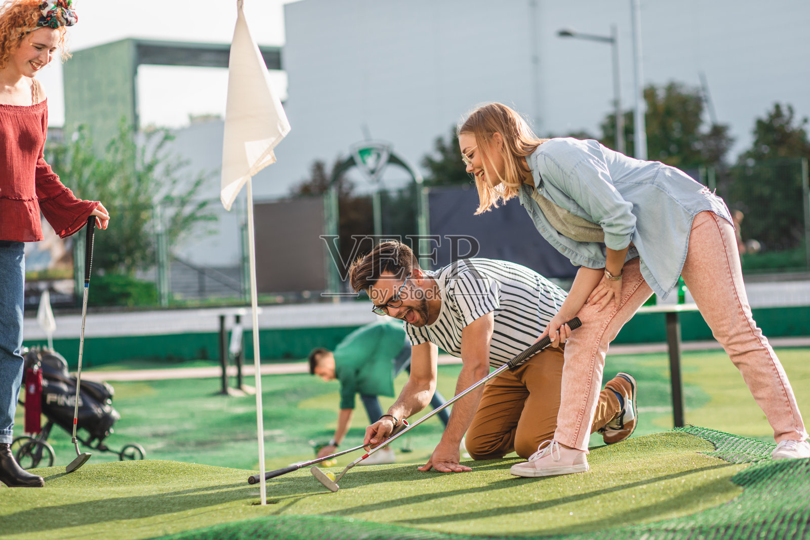 一群朋友在城市里一起玩迷你高尔夫。照片摄影图片