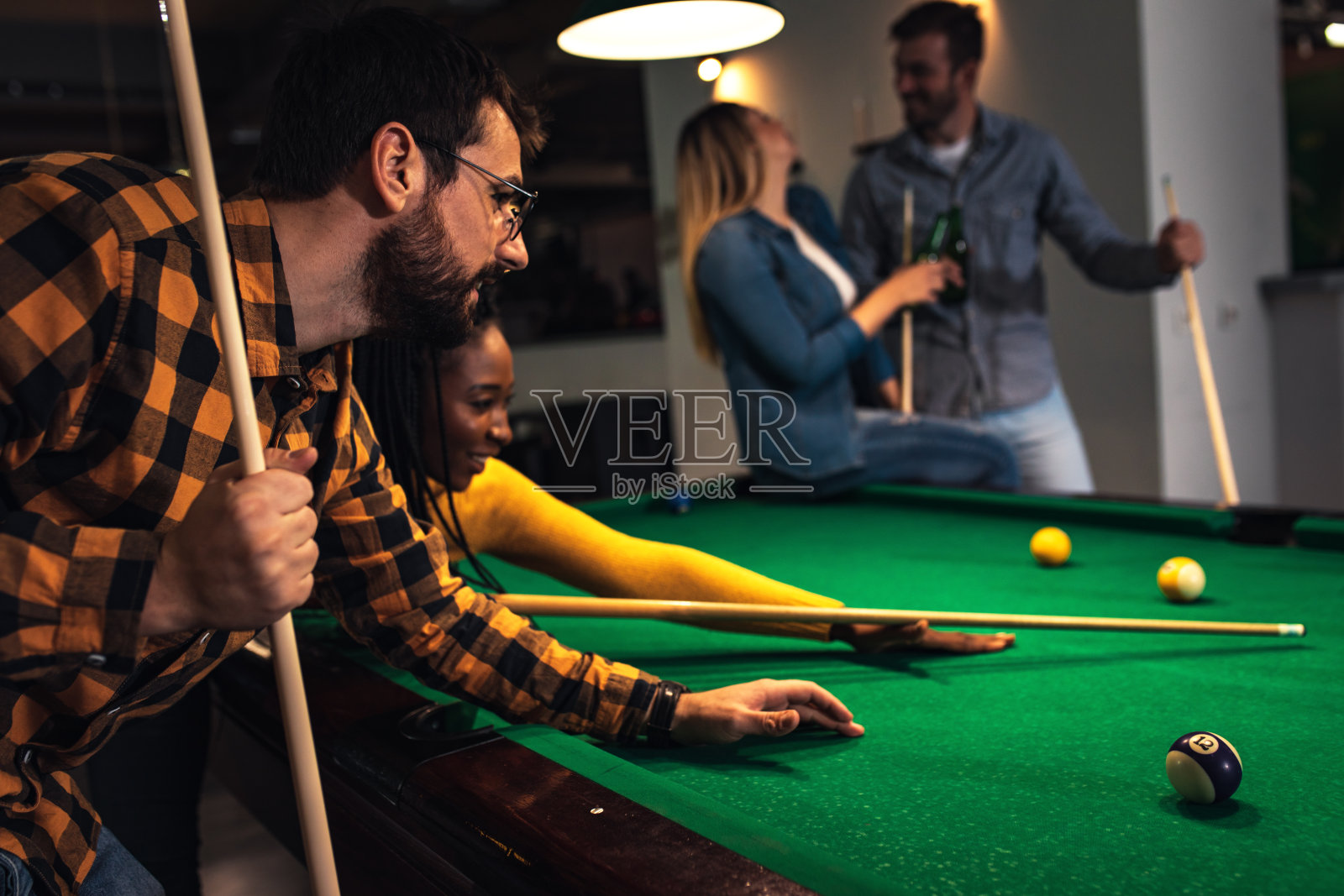 四个面带微笑的朋友在酒吧一起打台球。照片摄影图片