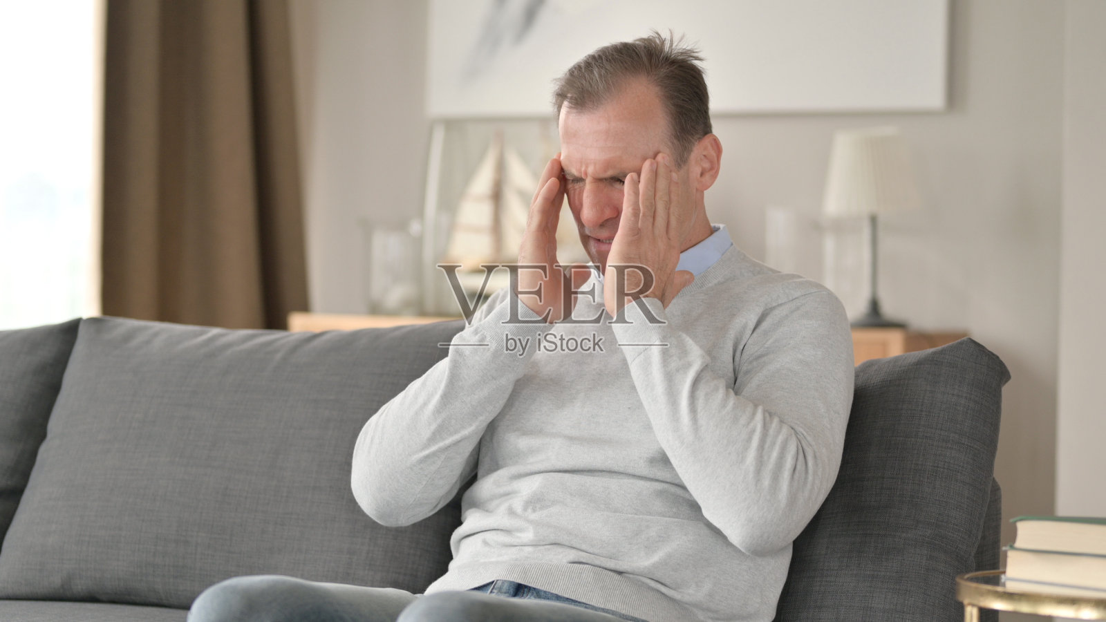 中年商人头痛地坐在沙发上照片摄影图片
