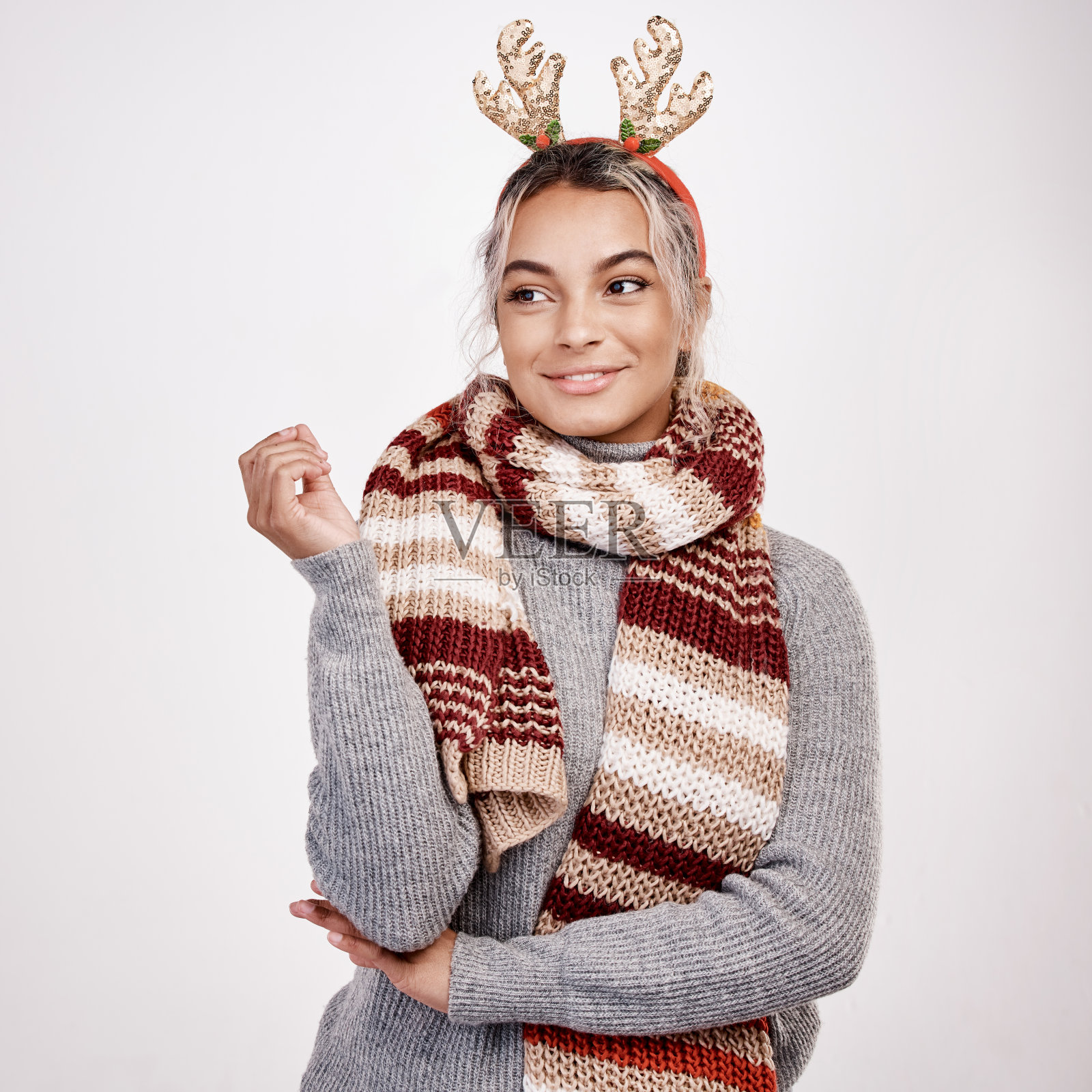 摄影棚拍摄了一个迷人的年轻女子，穿着圣诞主题服装，看起来若有所思照片摄影图片