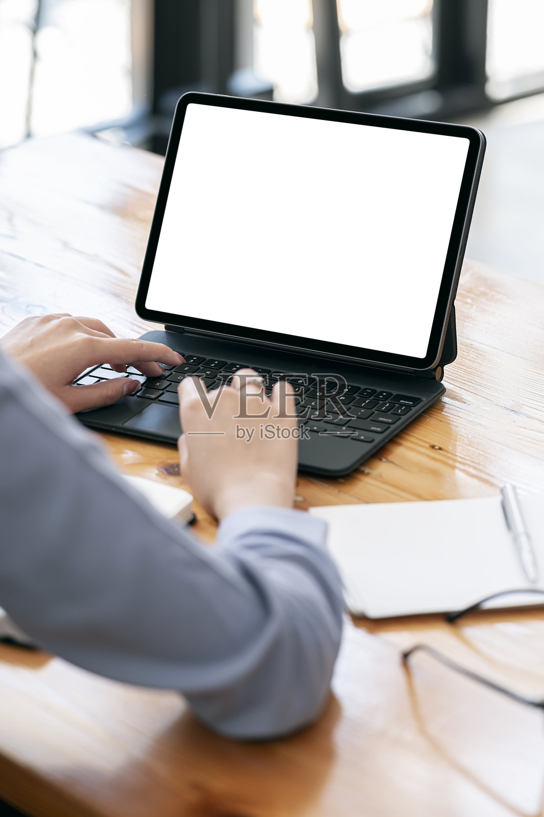 在垂直视图中，女人手在键盘上工作的平板电脑上的裁剪镜头。照片摄影图片