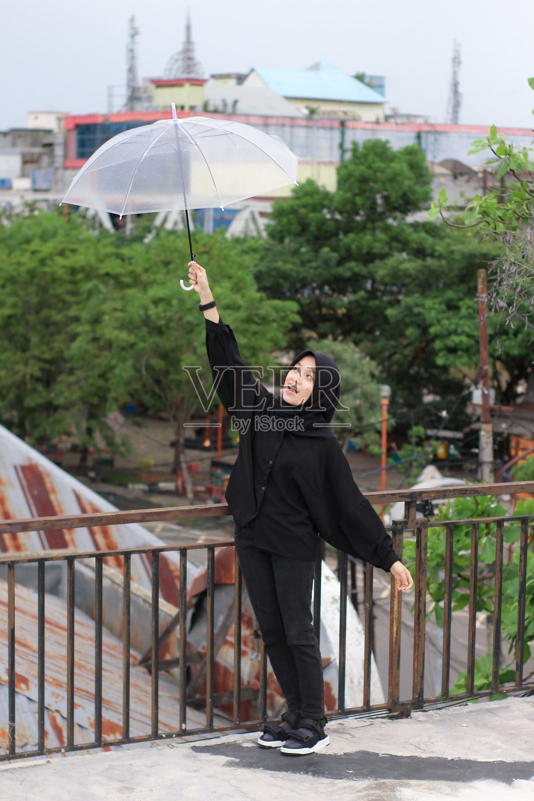 快乐的亚洲女人撑着伞站在城市公园里照片摄影图片