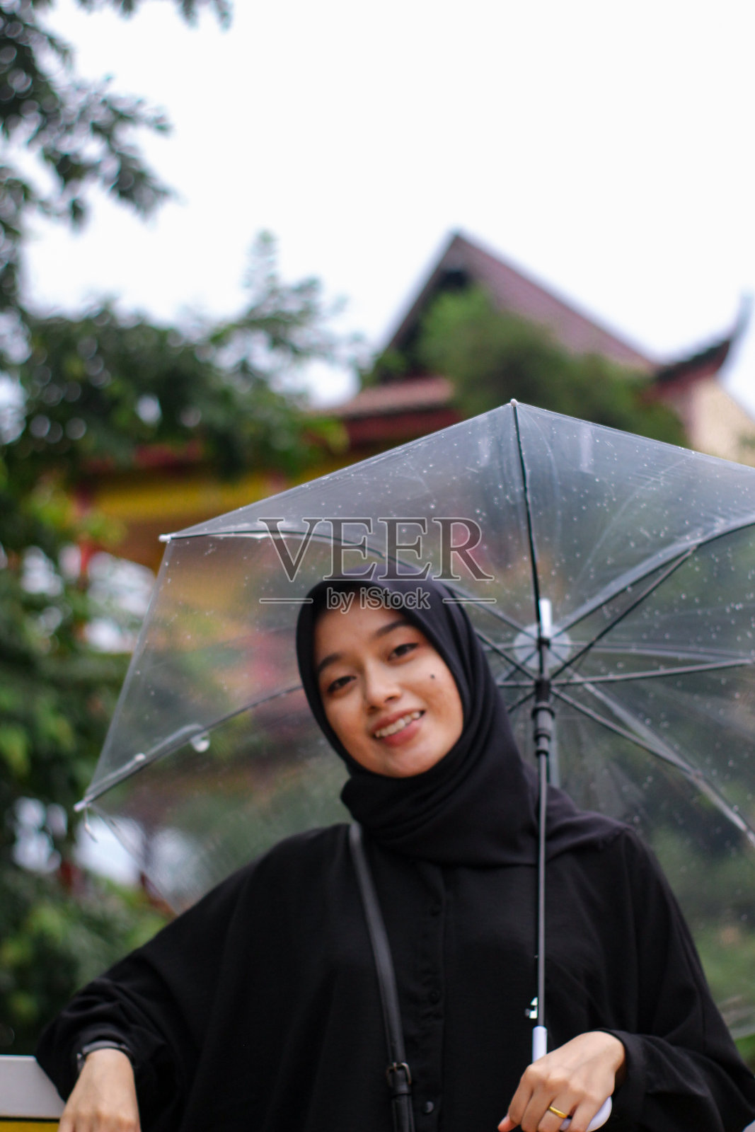 亚洲妇女打着伞站在城市公园里照片摄影图片