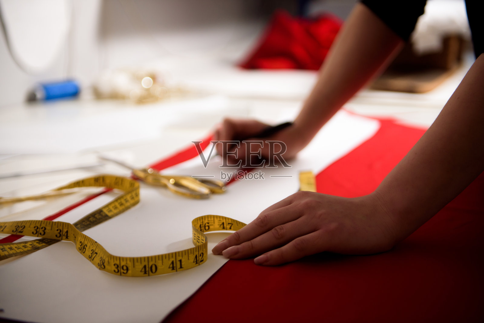 年轻的女裁缝在缝纫机上缝衣服。照片摄影图片