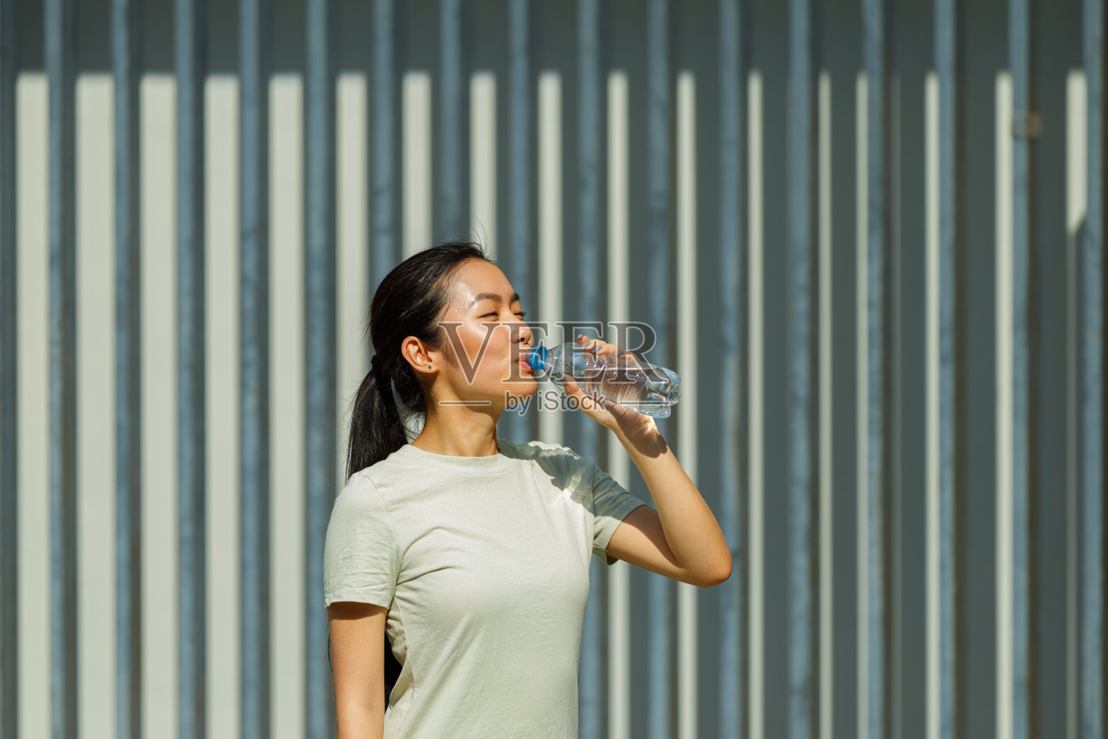 亚洲女士在街上训练后休息喝水照片摄影图片