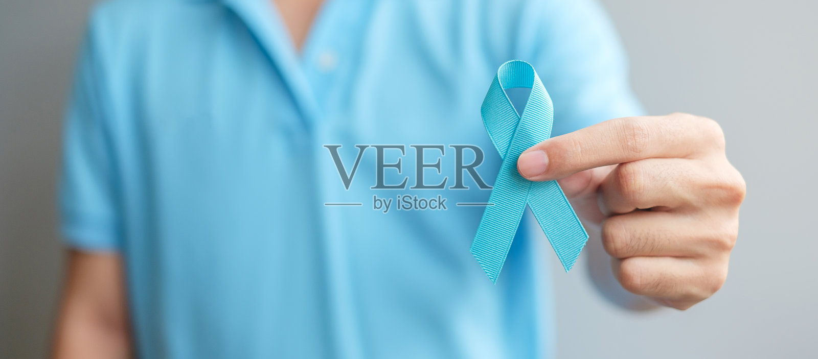 11月前列腺癌宣传月，身穿蓝色衬衫，手拿蓝丝带的男子支持活着和生病的人。医疗保健，国际男人，父亲和世界癌症日的概念照片摄影图片