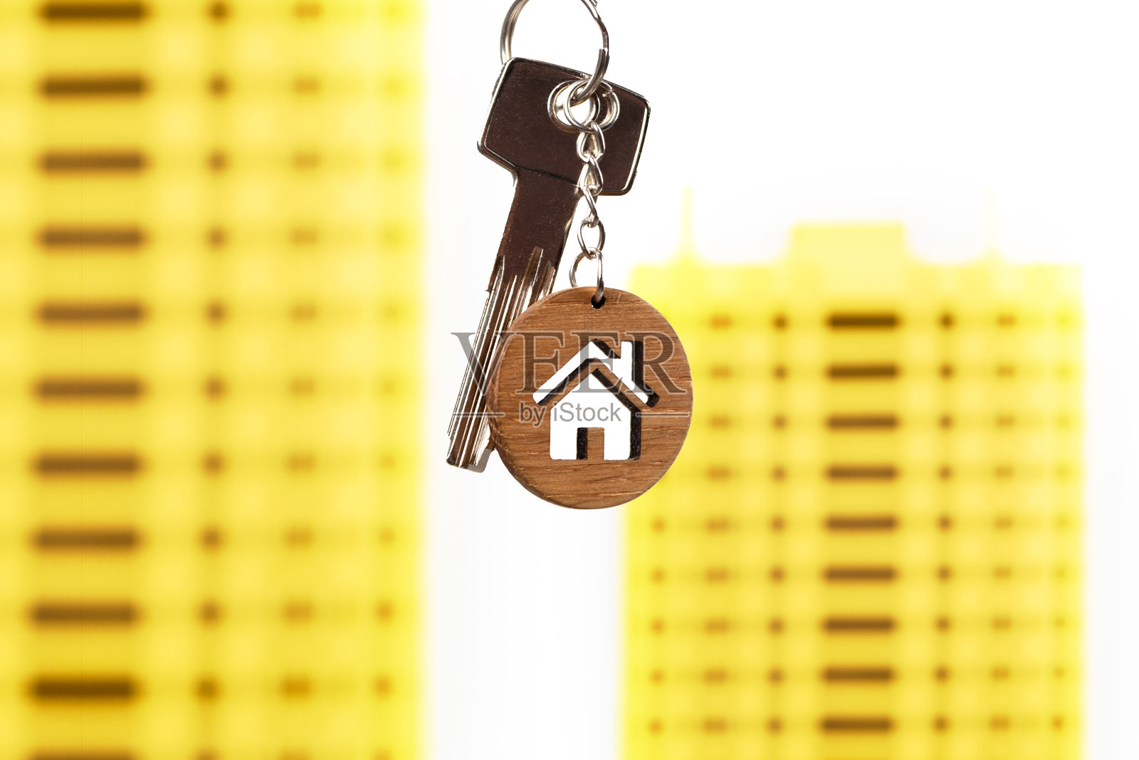 房地产的概念。房子形状的钥匙链与明亮的黄色房子模型。照片摄影图片