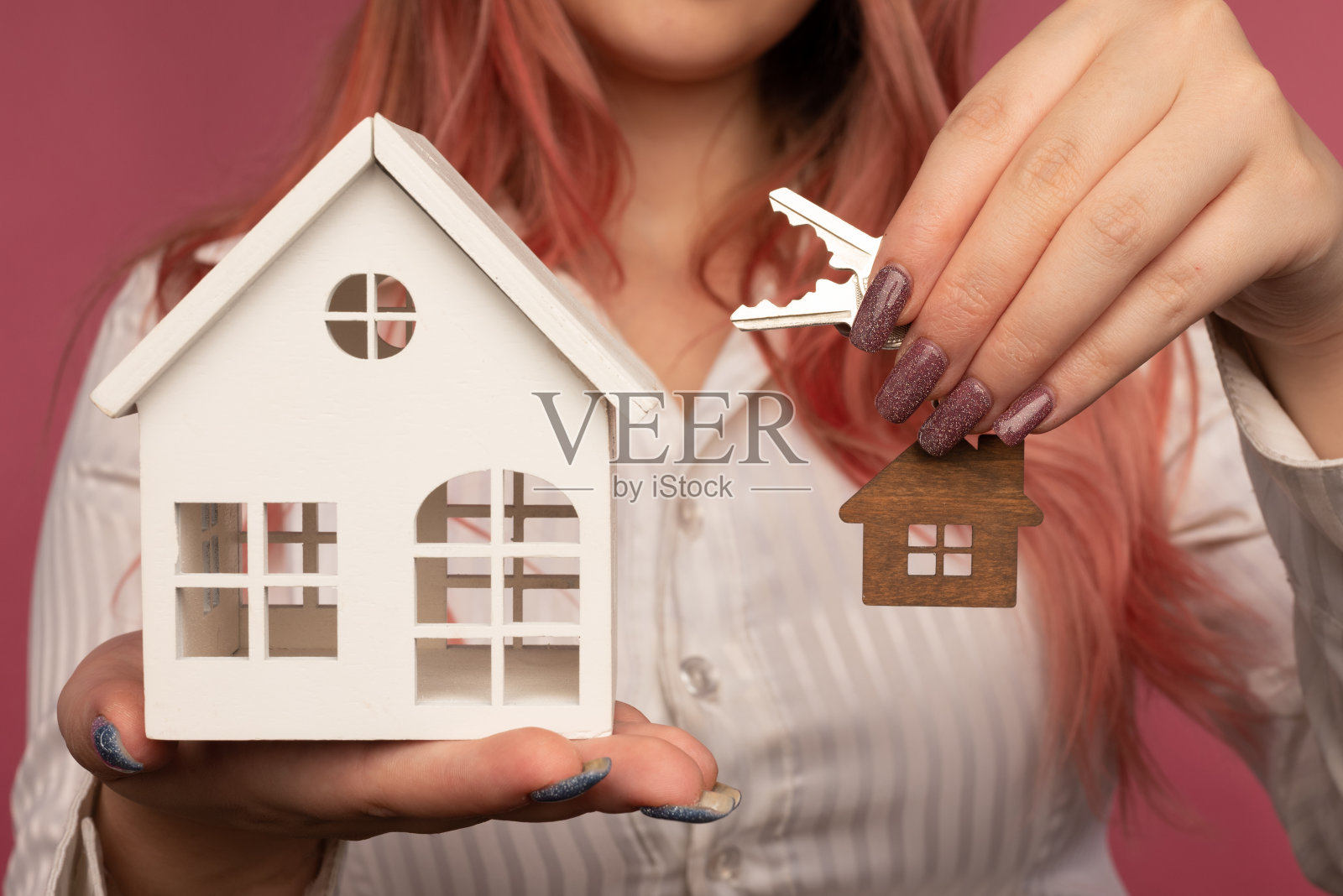 美丽的女性手握着钥匙，背景是一所房子照片摄影图片