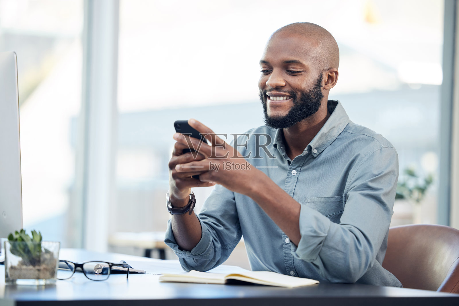 一个年轻英俊的商人独自坐在办公室里用手机照片摄影图片