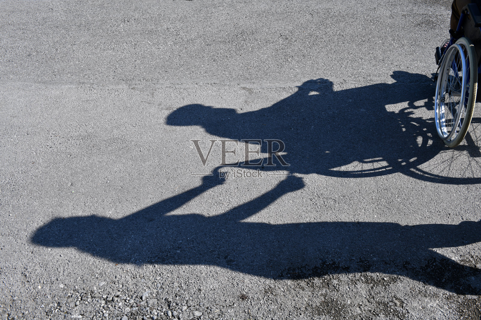 一个女人的影子驾驶在轮椅上的老人，沥青背景照片摄影图片