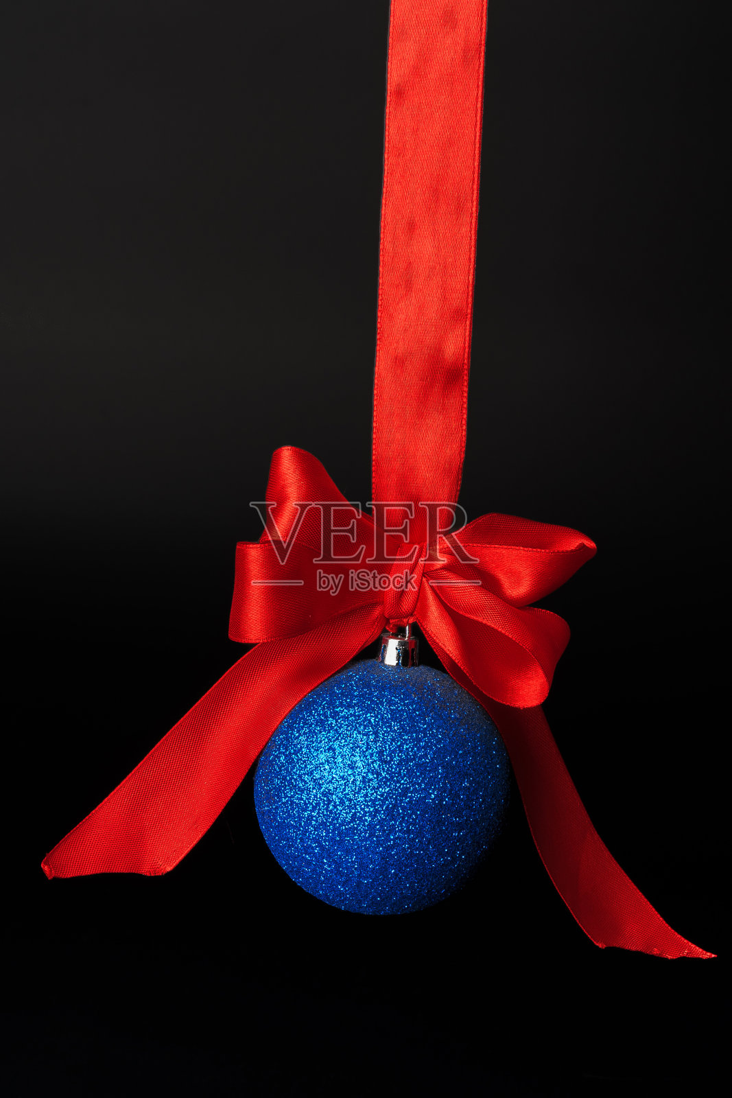 圣诞小玩意挂在黑色背景的红色缎带上照片摄影图片