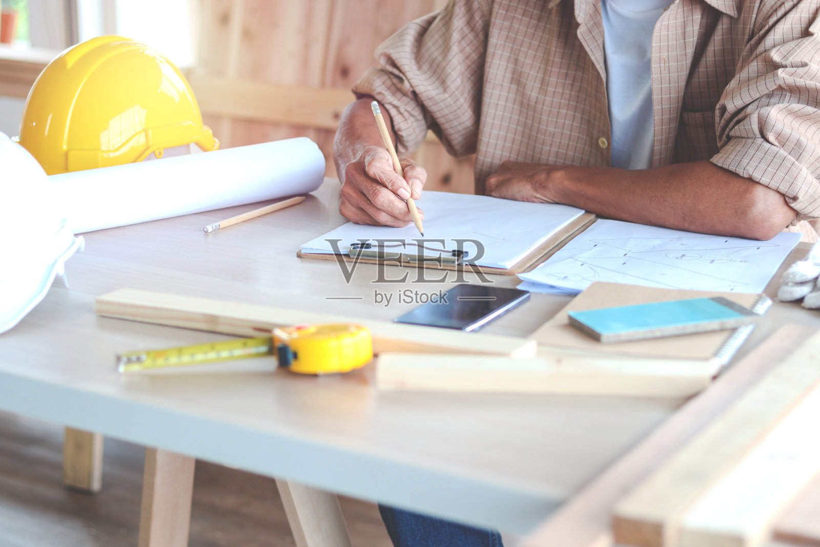 资深木匠在木工车间设计和绘制一块木头，木匠在工作台上使用不同的工艺工具，享受自己的DIY爱好照片摄影图片