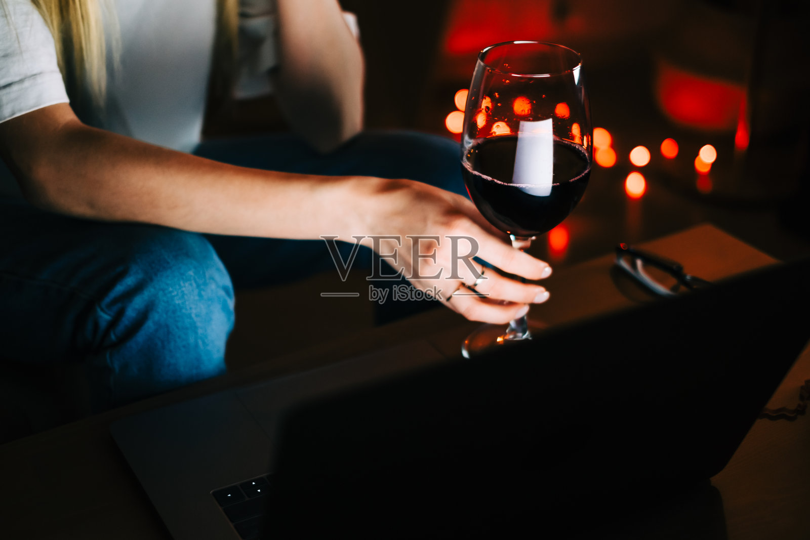 年轻的千禧一代女性在笔记本电脑上视频通话，喝着葡萄酒，利用科技与朋友或家人沟通。照片摄影图片