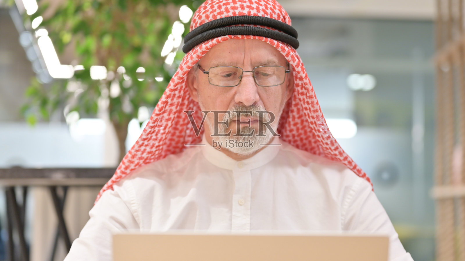 老阿拉伯商人在笔记本电脑上工作的特写照片摄影图片