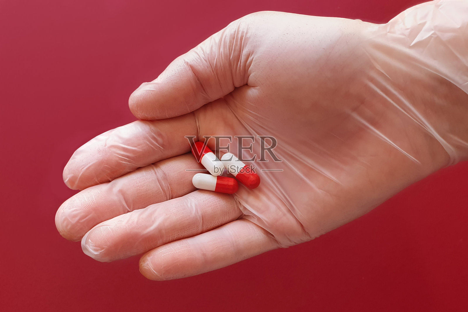 防护手套里有红色和白色的药丸。治愈冠状病毒和终结冠状病毒的概念。新的药丸研究概念。俯视图，生活方式照片摄影图片