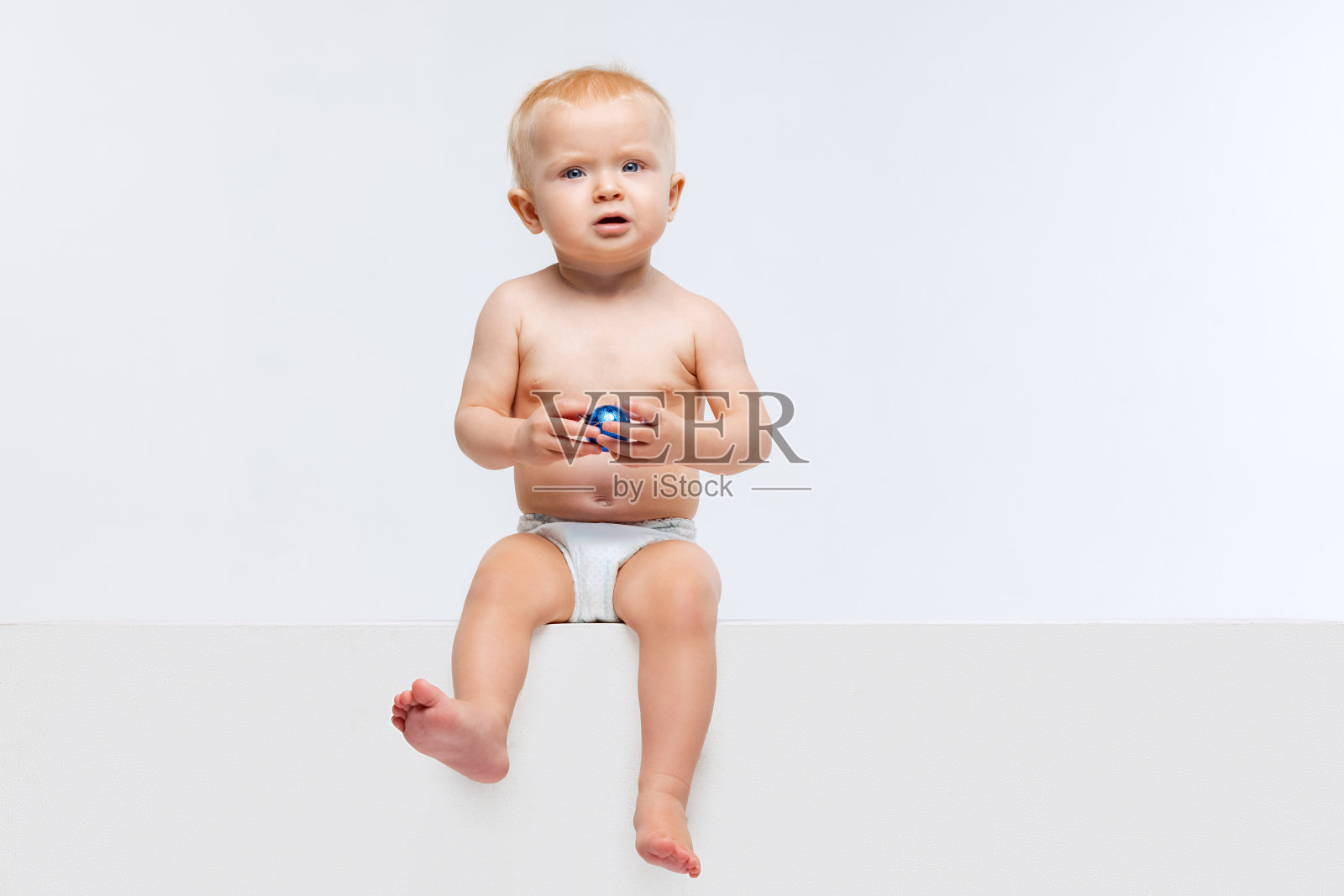 可爱的小女孩的肖像，婴儿平静地坐在和玩孤立的白色工作室背景。照片摄影图片