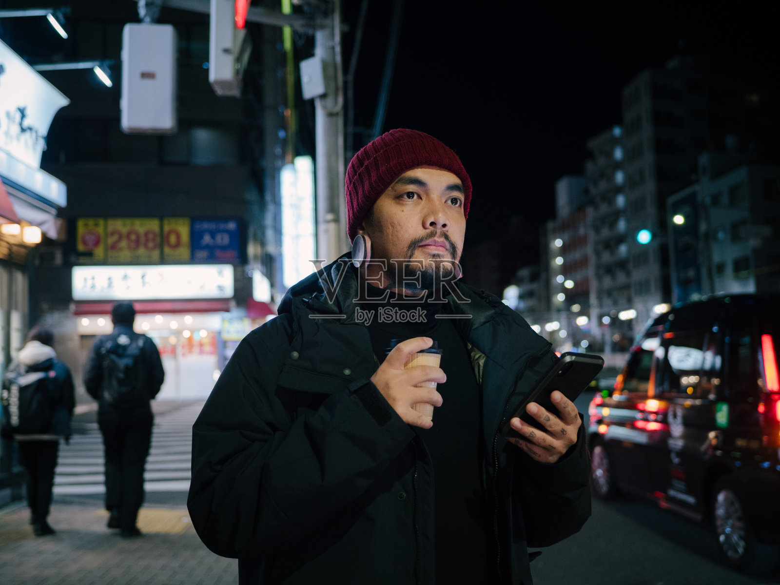 年轻的亚洲男子在东京等出租车或优步在晚上。照片摄影图片