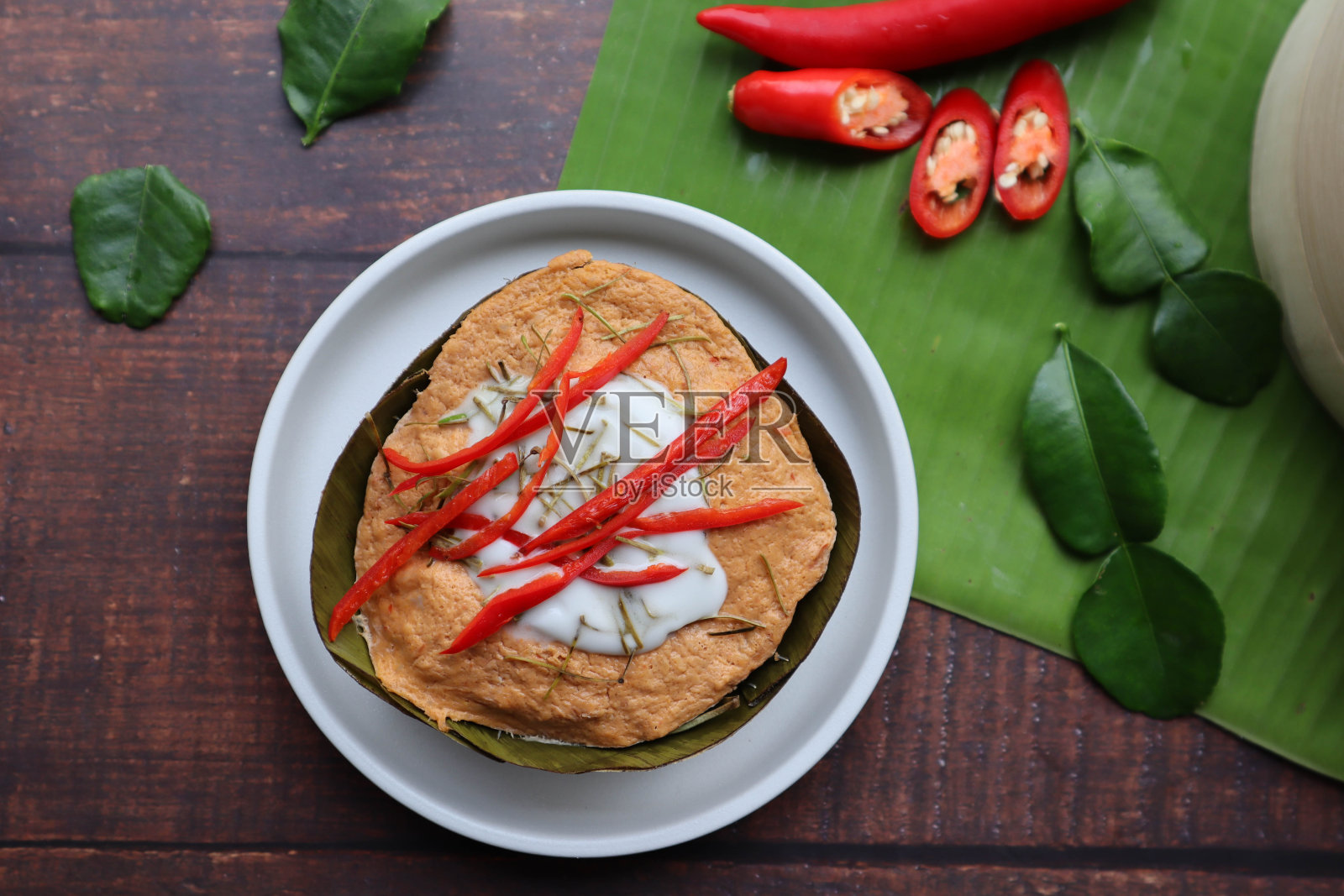 香蕉叶杯蒸咖喱鱼-著名的泰国食物称为Hor Mok或Amok在木桌上的俯视图照片摄影图片