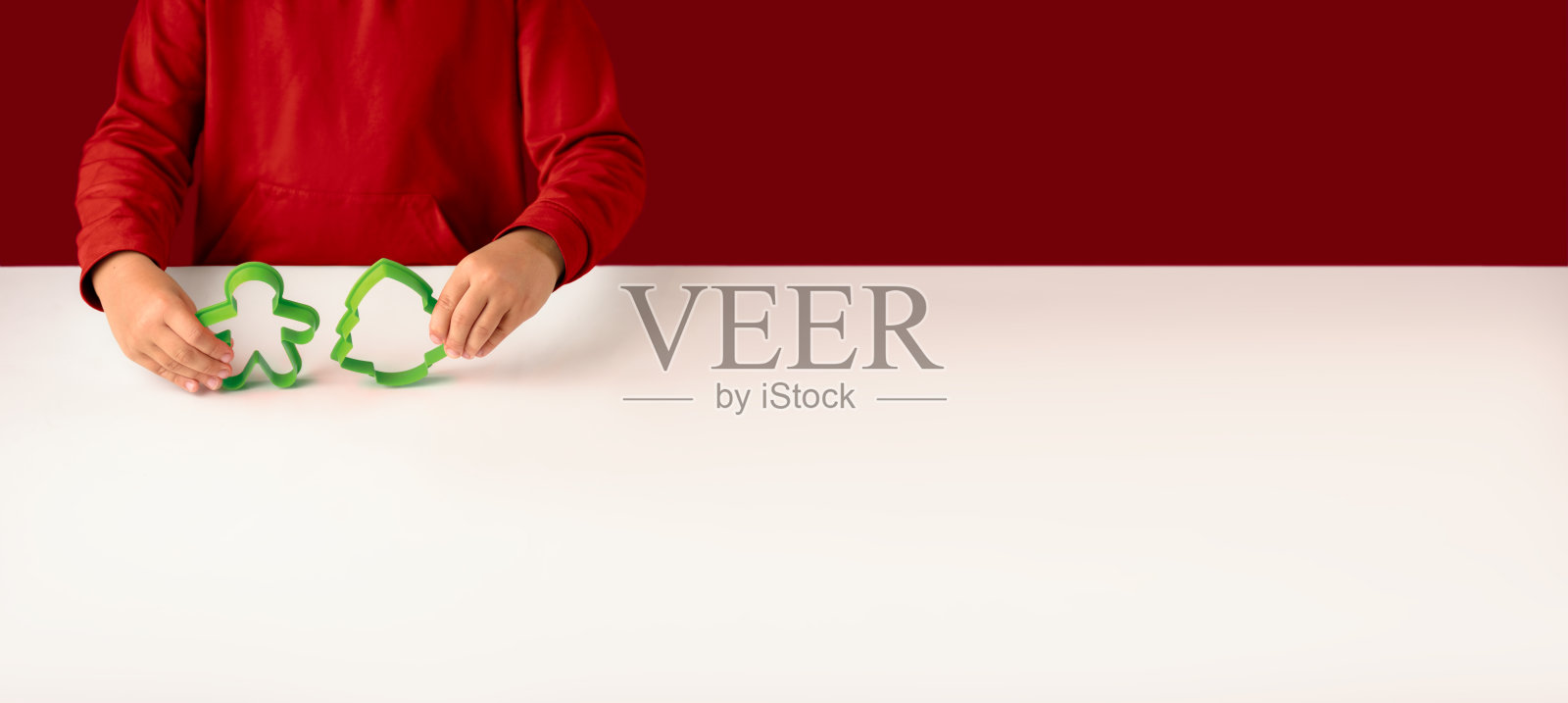 新年或圣诞节横幅与复制空间为您的文本。一个穿着红色毛衣的女孩拿着传统姜饼饼干的模具，形状是一个男人和一棵冷杉照片摄影图片