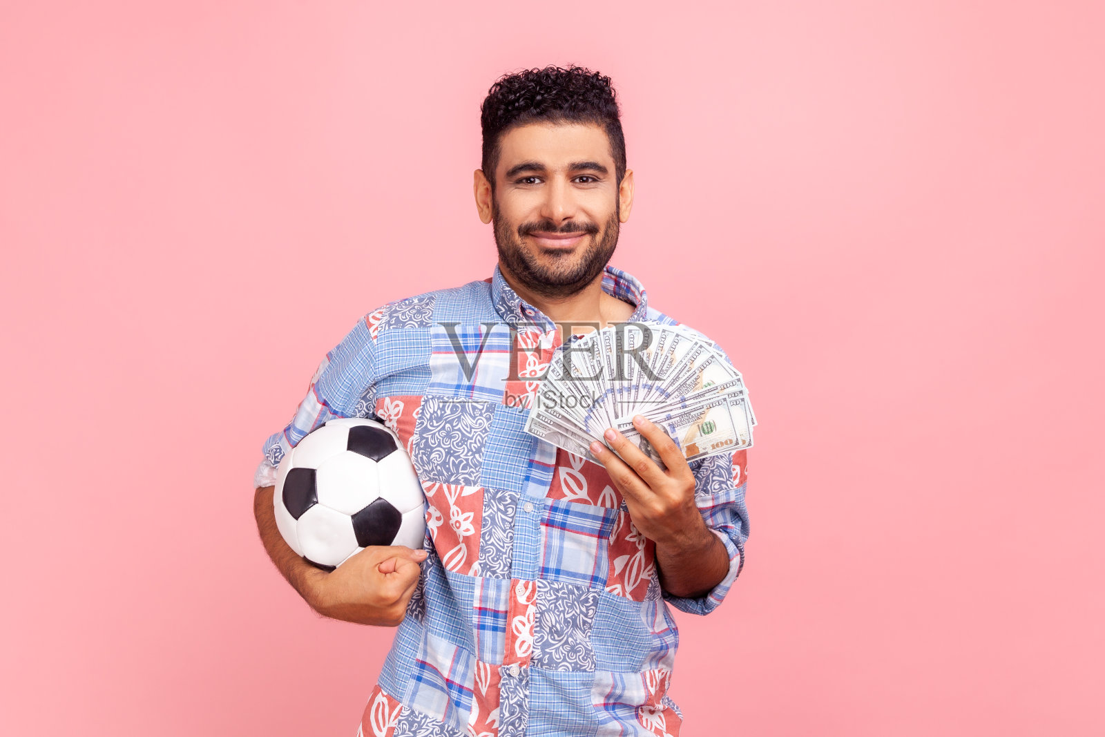 快乐微笑的男人拿着足球，炫耀着百元钞票的乐趣，赢得了很多钱照片摄影图片